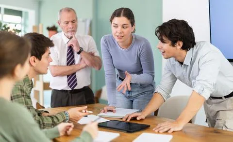 Students solving problems at table with teacher in background Stock-Fotos