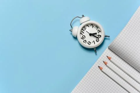 Students squared notebook and alarm clock on a blue background with copy spac Stock Photos