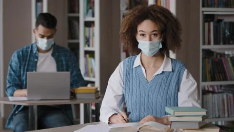 Students study in library young woman in protective mask writing notes does Video stock 178096469