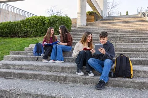 Students studying and collaborating on campus stairs using digital tablet Foto stock