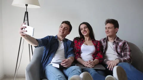 Students take a selfie together while sitting on a sofa at home. Young friends Video stock 130541540