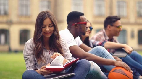 Students taking books in the library read them on the street. Stock Footage 130049395