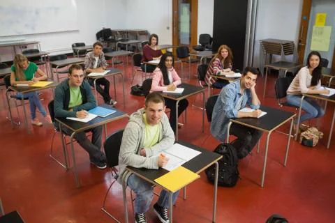Students taking notes in class smiling up at camera Stock Photos