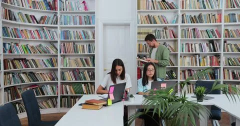 Students team study together using laptop prepare for exam in library Stock Photos
