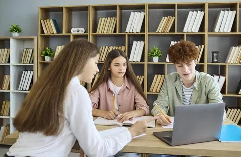 Students team working on laptop in library, writing notes for group project Stock Photos