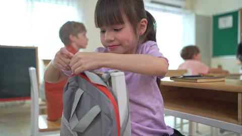 Students turn to retrieve their stationery from backpacks hanging Video stock 339327404
