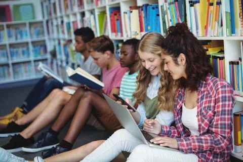 Students using mobile phone and laptop in library Stock Photos