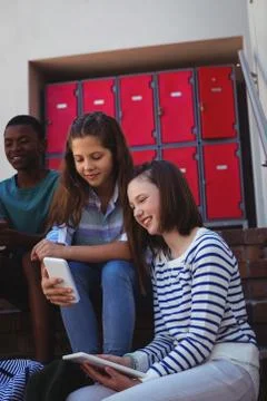 Students using mobile phone and digital tablet on staircase Stock Photos