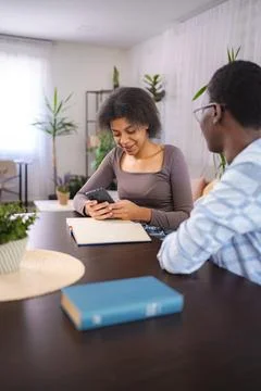 Students using mobile phone and studying at home Stock Photos