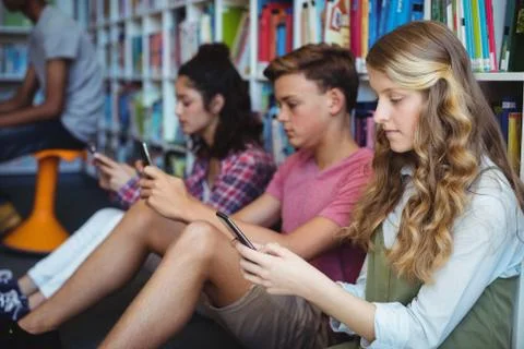 Students using mobile phone in library Stock Photos