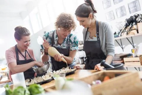 Students using piping bag in cooking class kitchen Stock Photos