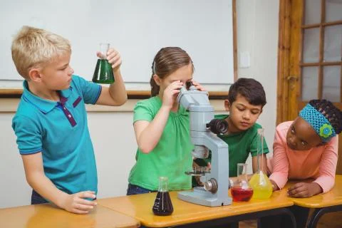 Students using science beakers and a microscope Stock Photos
