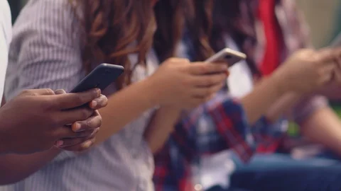 Students using their smartphones sitting outdoors on a green grass. Stock Footage 126723129