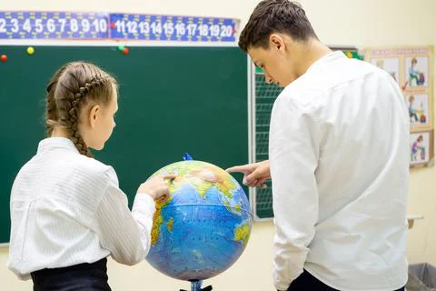 Students view a globe in a geography lesson, fulfilling the teacher's task Stock Photos