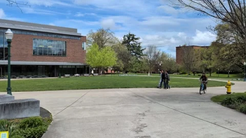 Students walk and ride bicycles around a circular University of Oregon campus Stock Footage 343894804