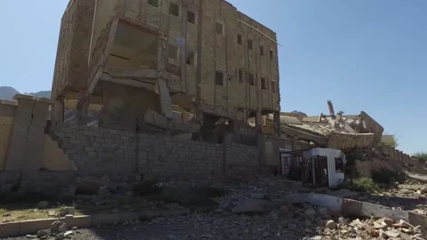 Students walk by their school, destroyed by the violent war in Yemen Stock Footage 197048569