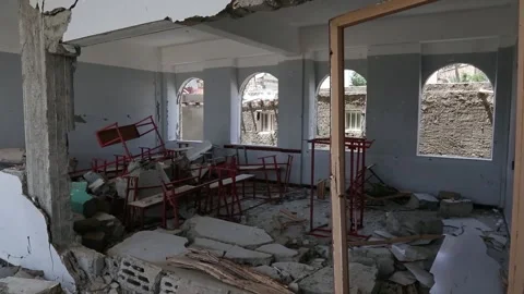 Students walk by their school, destroyed by the violent war in Yemen Stock Footage 197048683