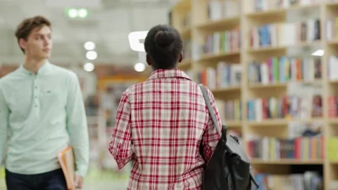 Students walking in college library Stock Footage 142550787