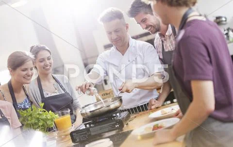 Students watching chef teacher in cooking class kitchen Stock Photos