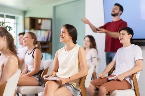 Students watching a presentation with a teacher in the background Stock Photos