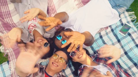 Students waving hands on camera laying on the ground. Video stock 127912980