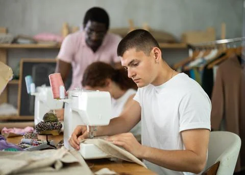 Students work with sewing machines under guidance of teacher 库存照片