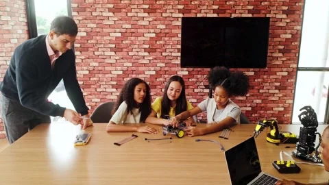 Students work together assembling a robotic vehicle in a coding class. Video stock 313478397