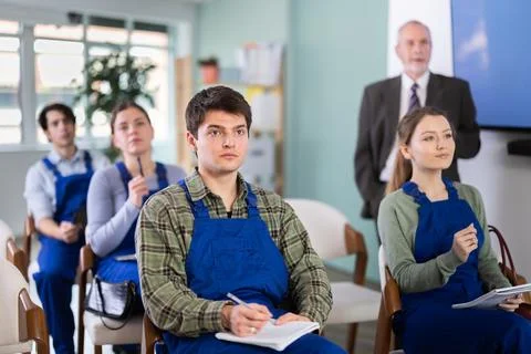 Students workers listening in lecture hall with professor in background Stock Photos