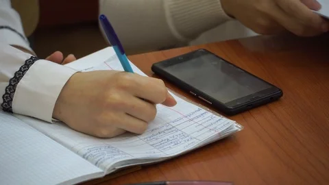 Students write in a notebook, sitting at the table of the university. Near the p Stock Footage 100033325