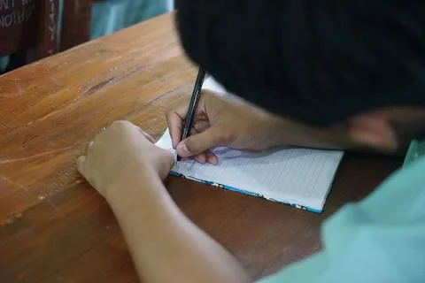 Students writing and recording learning outcomes given by the teacher in clas Stock Photos
