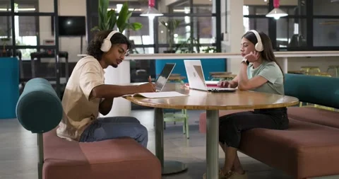 Students writing and typing, preparing for deadline at round wooden table with Stock Footage 335867206