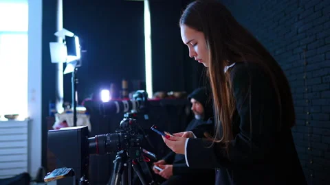 Studio Assistant Checking Smartphone Beside Video Camera. Assistant checks Stock Footage 334812827