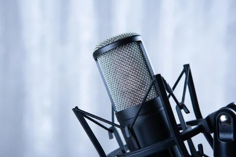 Studio black condenser microphone against gray curtains Stock Photos