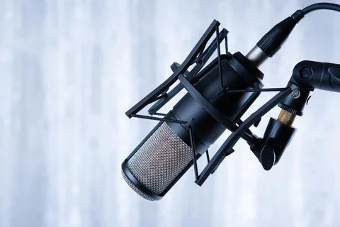 Studio black condenser microphone against gray curtains Stock Photos