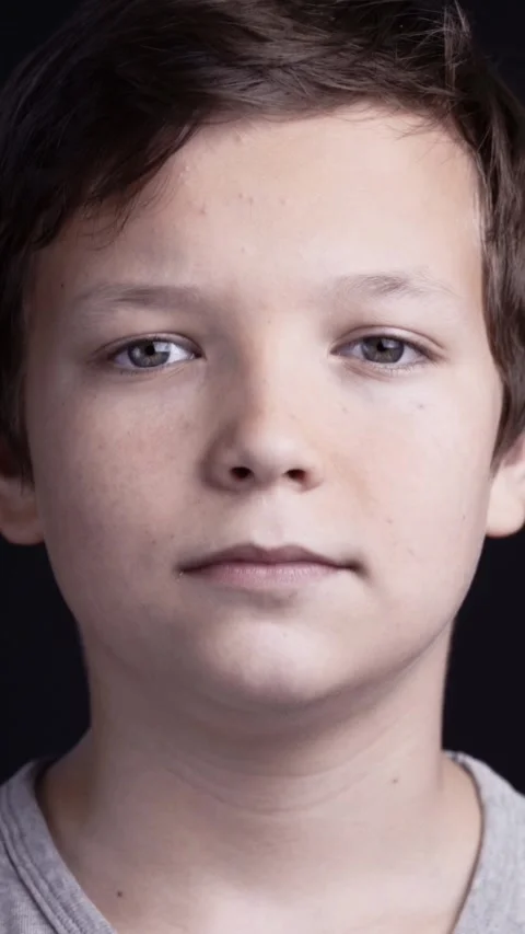 Studio close-up portrait of a serious young Caucasian boy with brown hair Stock Footage 344768289