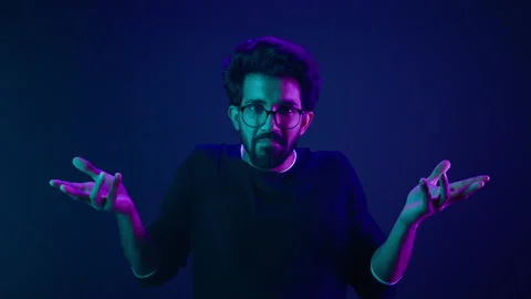 Studio dark blue neon background Indian man Arabian male model guy confused Stock Footage 239637199