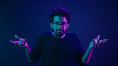 Studio dark blue neon background Indian man Arabian male model guy confused Stock Photos