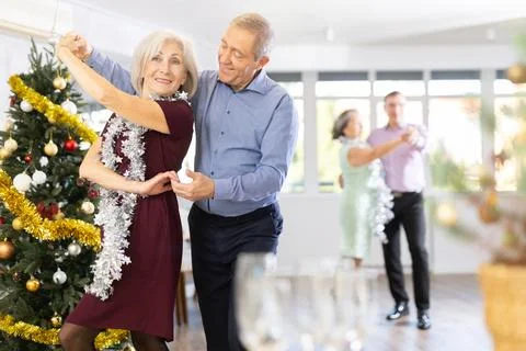 In studio decorated for New Year, elderly couple perky dance pair discofox Fotos Stock