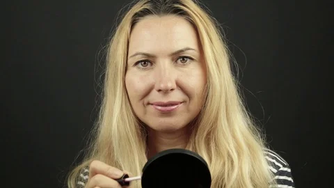 Studio light woman portrait while putting lipstick on her lips Stock Footage 93079250