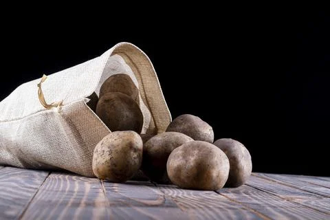Studio lighting. black background. potatoes are planted from a bag on a retro Stock Photos