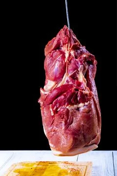 Studio lighting. dark background. a piece of meat is suspended on a hook. Clo Stock Photos