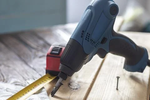 Studio lighting. electric impact screwdriver. Wooden background in retro styl Stock Photos