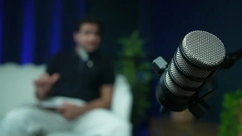 Studio microphone with a blurry male speaker talking in the background Stock Footage 337205062