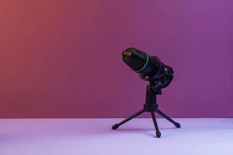 Studio microphone on tripod stands against vibrant pink backdrop forming clea Фото
