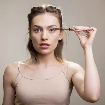 Studio photo of model enhancing long lashes with mascara for a natural dewy look Stock Photos