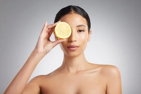Studio Portrait of a beautiful young mixed race woman holding a lemon. Hispanic Stock Photos