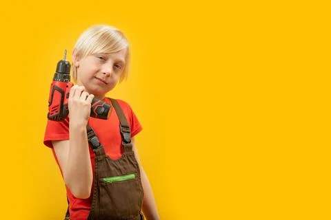 Studio portrait of blond boy in work clothes with drill in his hands in isola Stock-Fotos