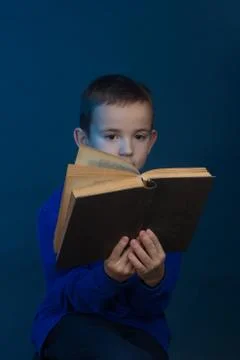 Studio portrait of boy on a blue background in a classic t-shirt. Holding a b Stock Photos
