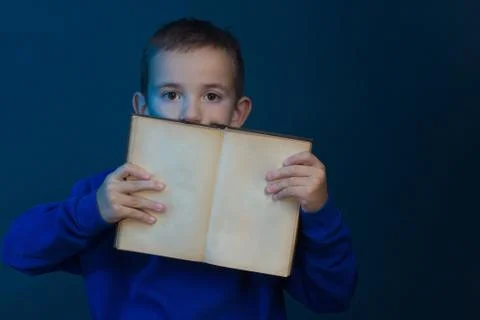 Studio portrait of boy on blue background in a classic t-shirt. he holds an o Stock Photos