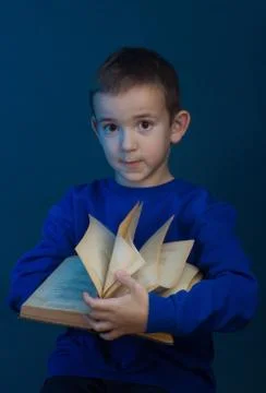 Studio portrait of boy on blue background in a classic t-shirt. Holding a boo Stock Photos